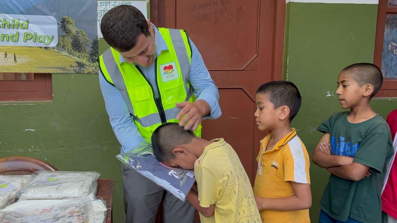 A volunteer handing a clothing package to a boy while other children wait