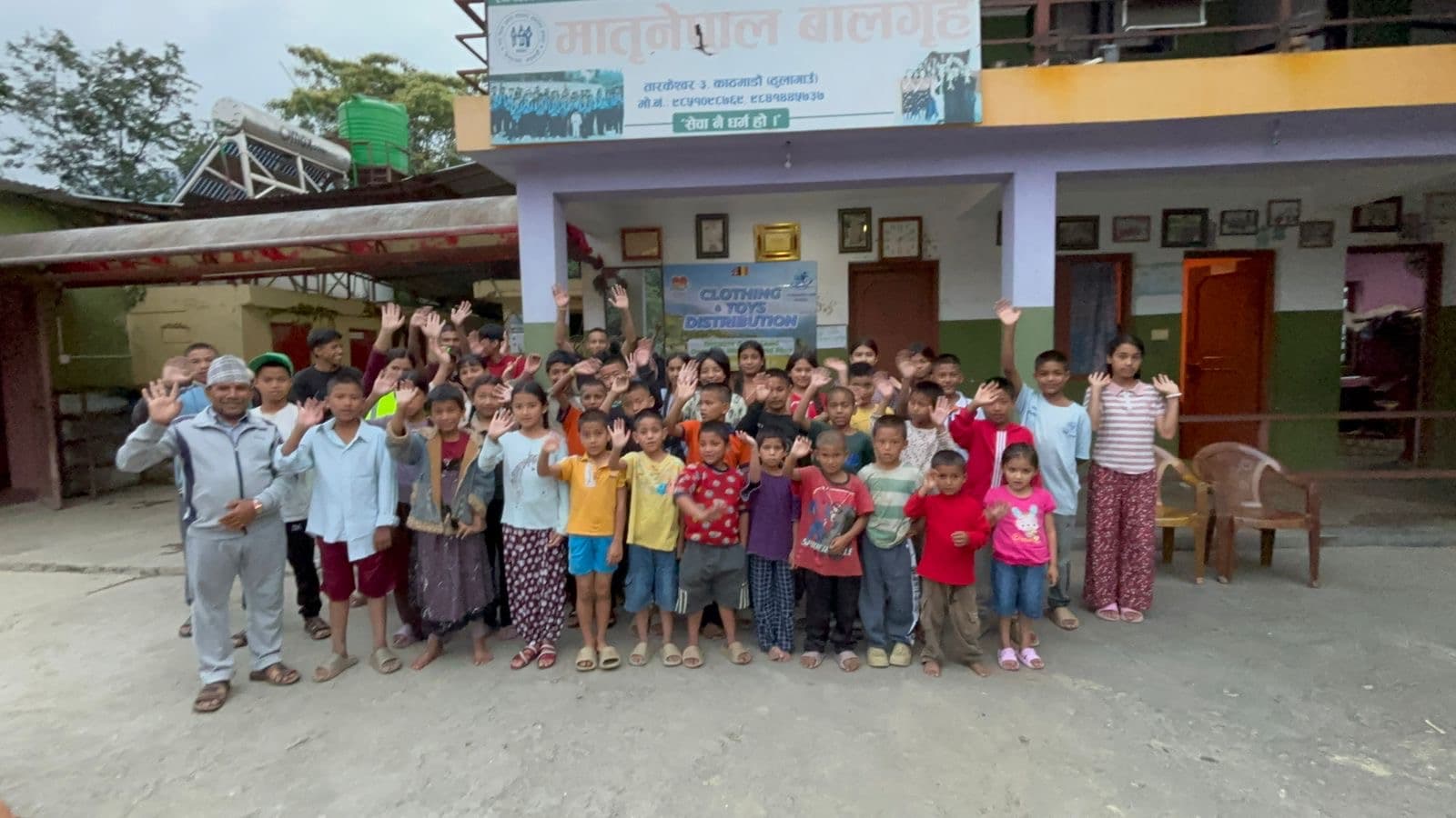 Children and staff waving in front of the children's home