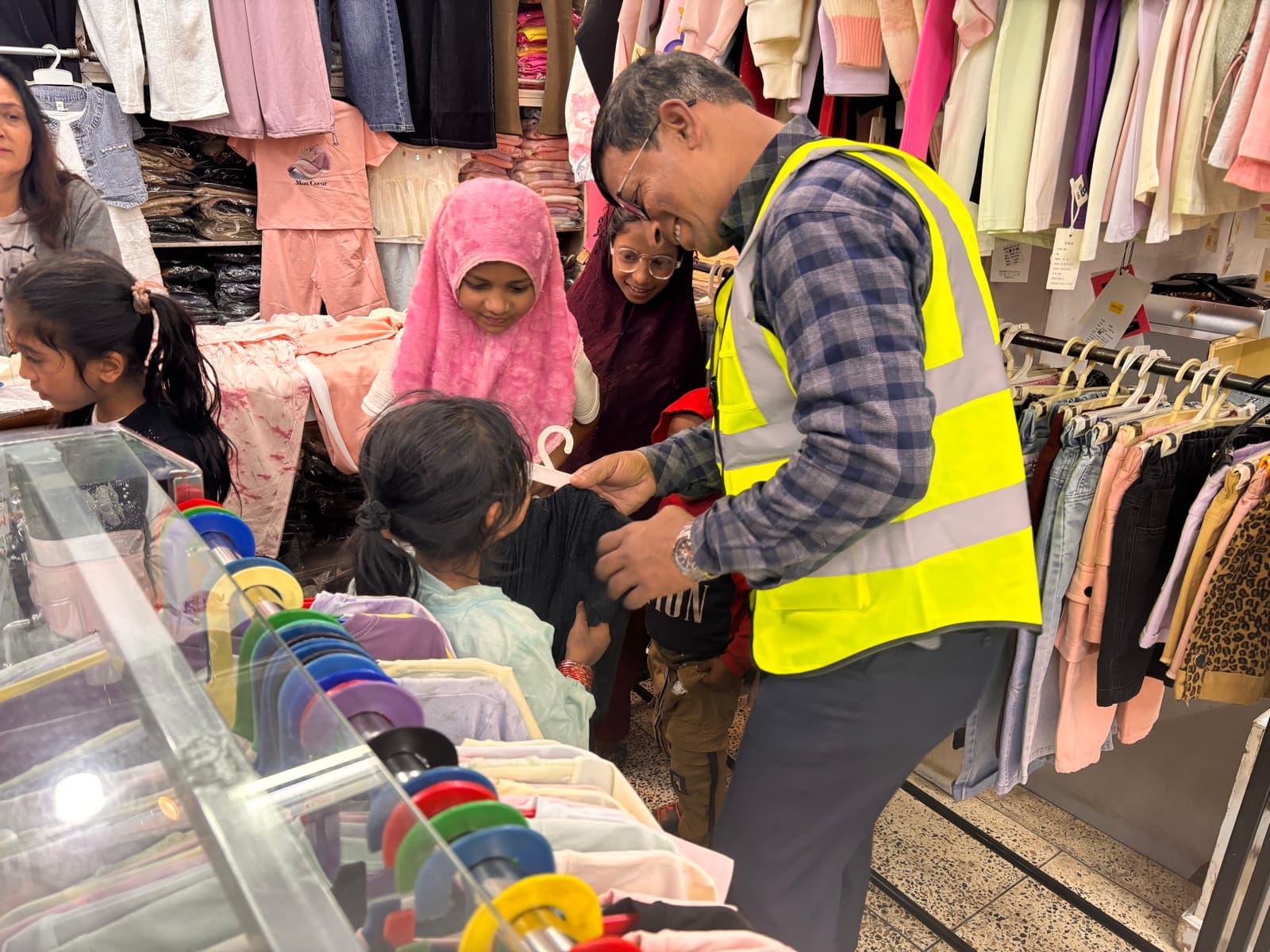 A volunteer helping a girl choose clothes in a shop