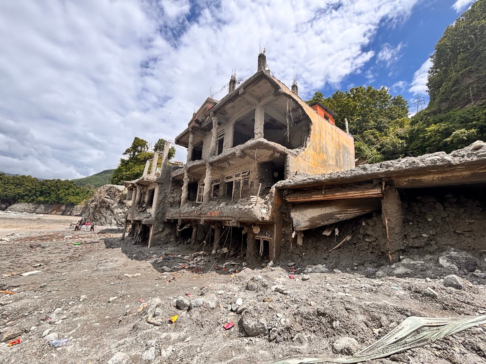A house partly destroyed by the flash flood, surrounded by mud and debris