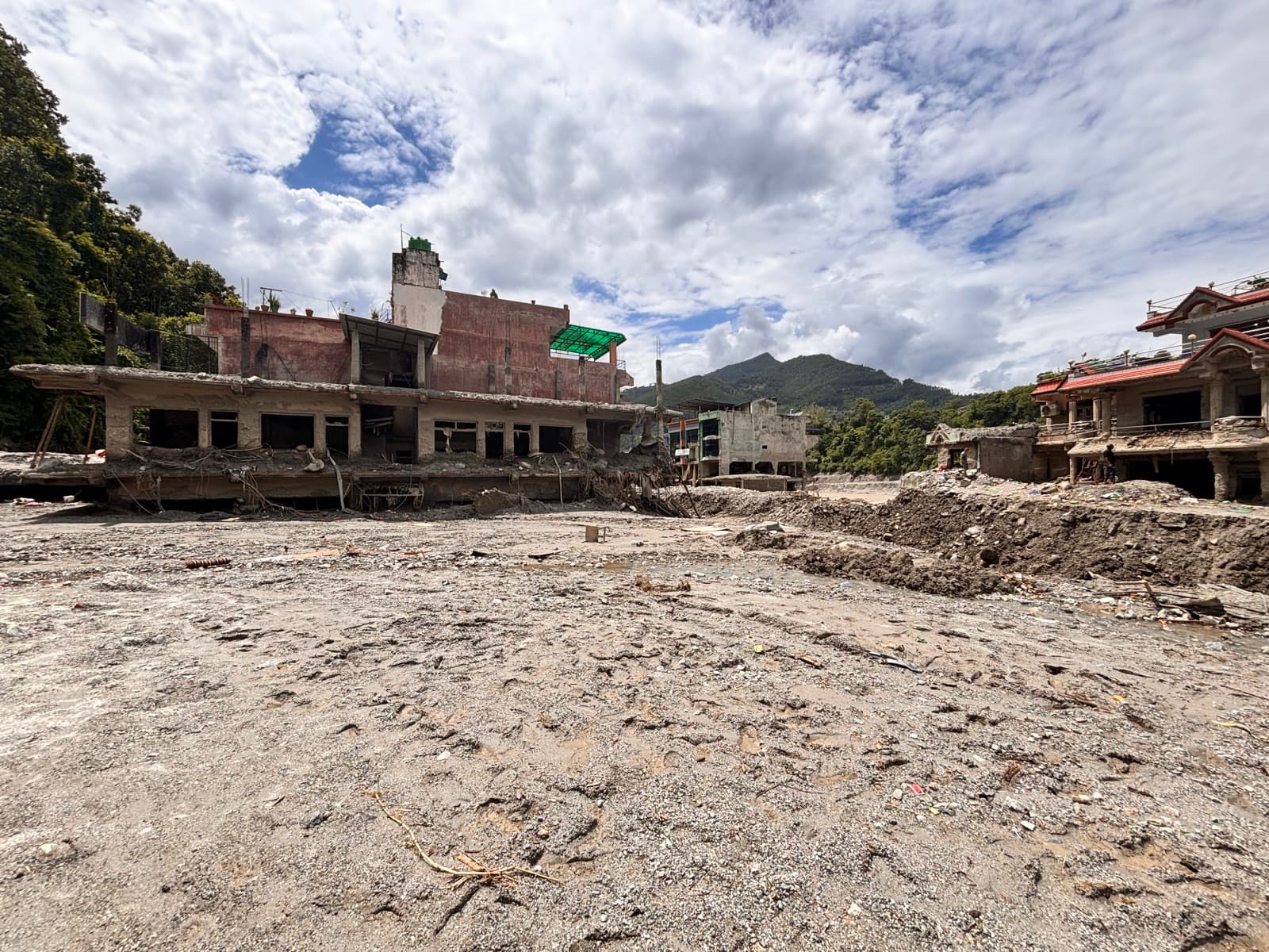Damaged buildings and a wide field of mud left by the flood