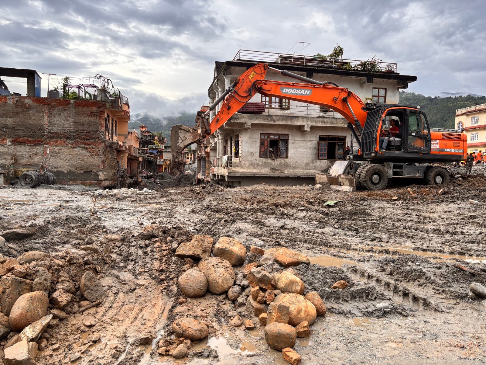 An excavator clearing stones and debris after the flood