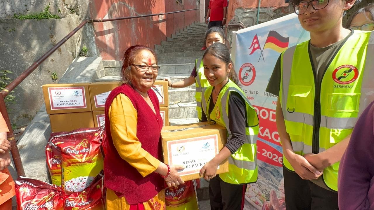 A student volunteer handing a food package to a smiling older woman