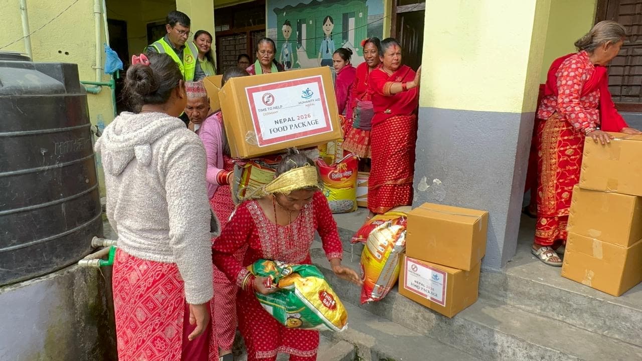 Women carrying food packages and rice bags away from the distribution