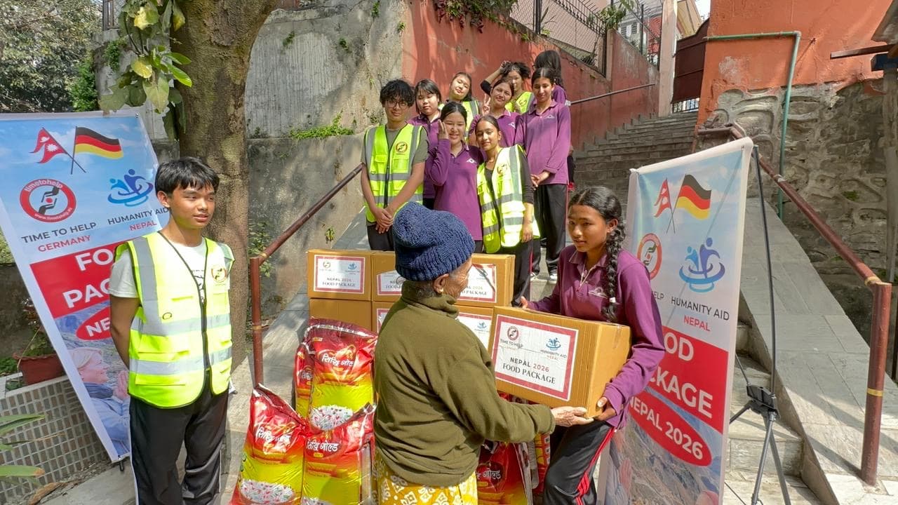 A student volunteer handing a food package box to an older woman in front of stairs