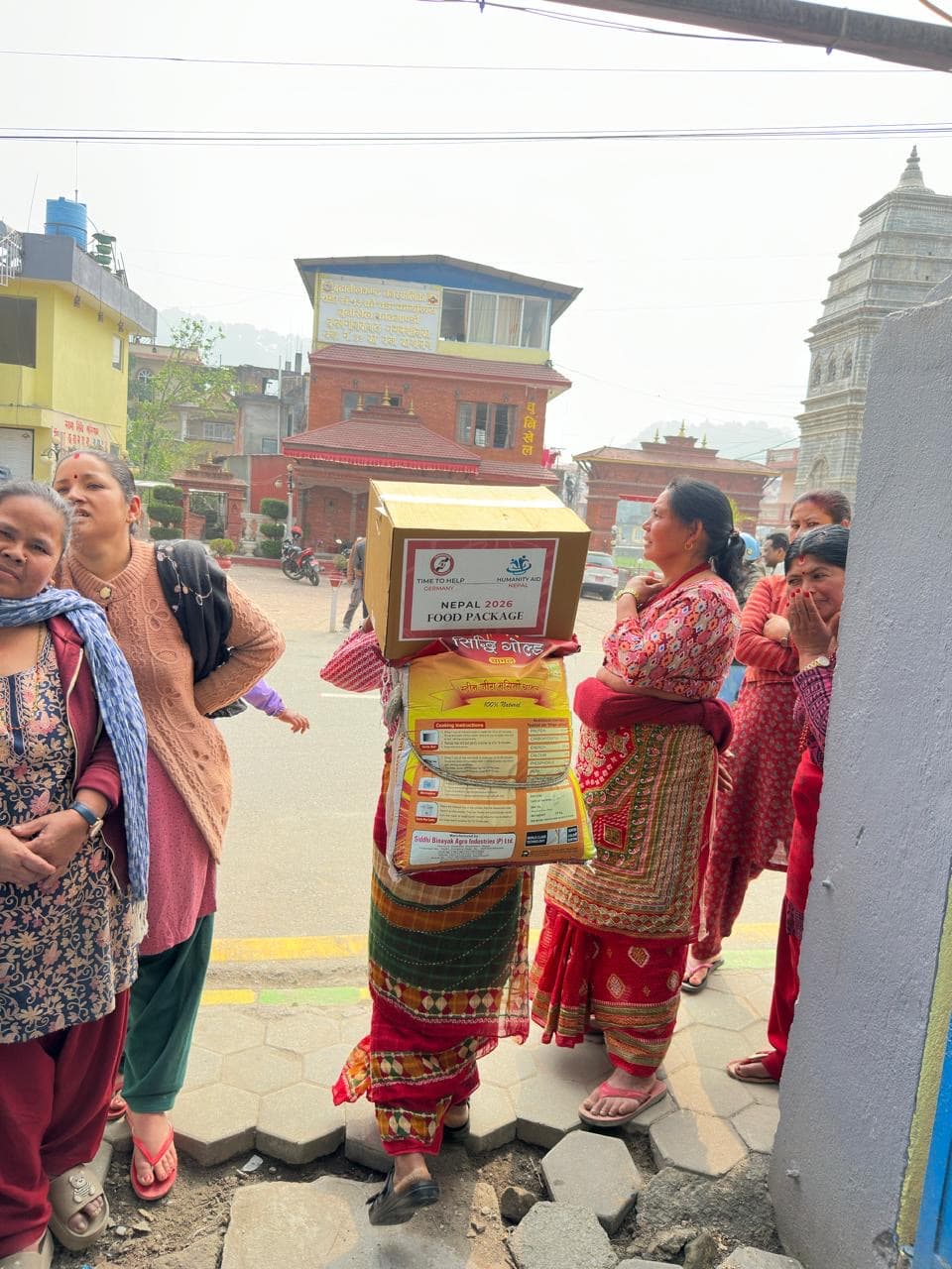 A woman carrying a food package box and a rice bag home