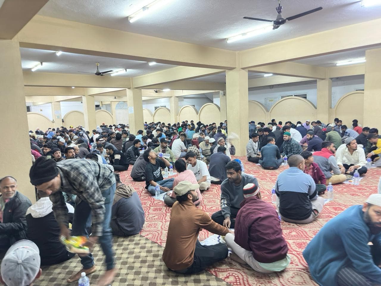 People sharing iftar meals in a community hall
