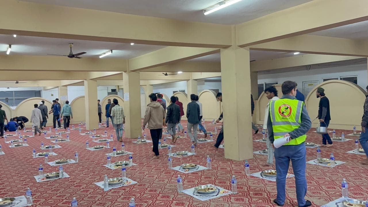 A TimeToShare volunteer and helpers setting out iftar plates in the hall